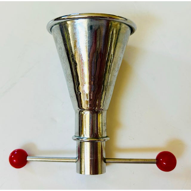 A rare Art Deco mechanical "Trap Jigger" in chrome with red bakelite accents made by Fay. When the arms of the filled...