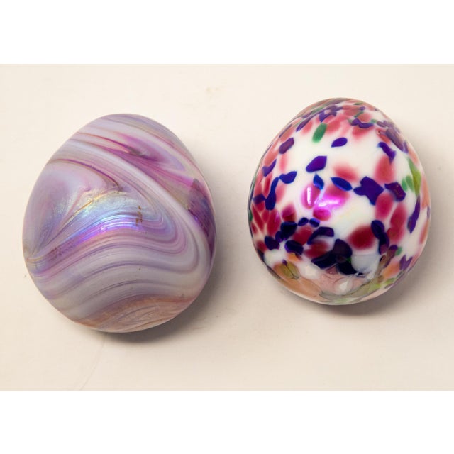 Offering a unique pair of art glass eggs. One is white with blue, green and pink dots, and the other is iridescent in...
