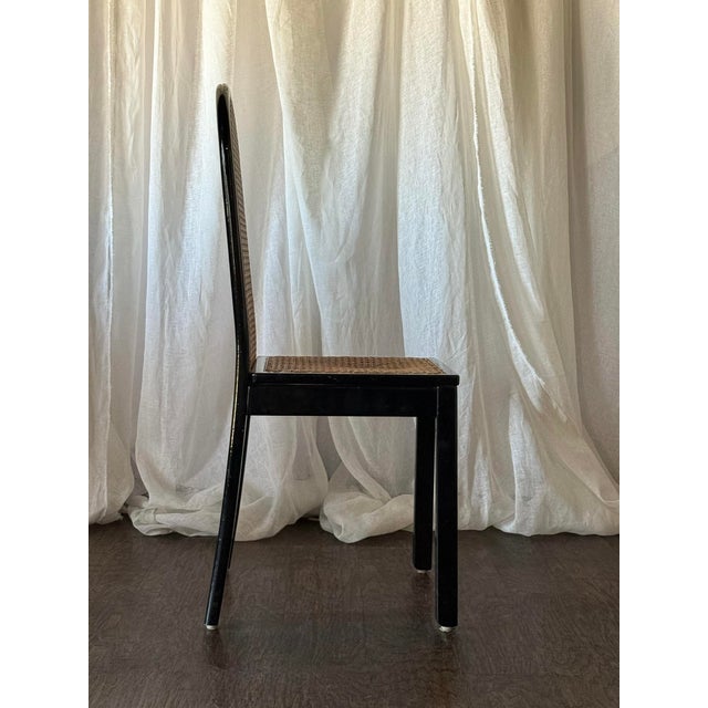 This set of four black-painted cane chairs features graceful arched backs and woven cane panels that bring a classic...