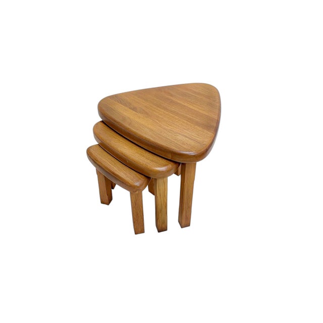 A set of three nesting tables in a dark brown color, solid oak, oval/kidney shaped in the style of Pierre Chapo,ca 1970....