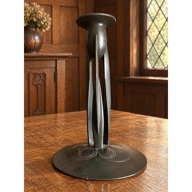 Three tall, open supports connect a wide circular foot to the candle socket, with looping Celtic decoration spreading...