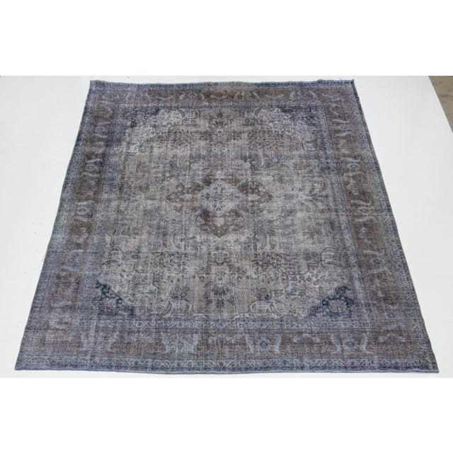 This is a gray, antique, hand-knotted Persian wool rug with an all-over floral design with brown and blue accents. This...