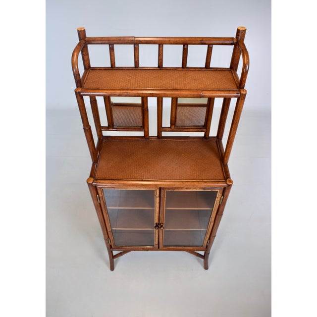 An impressive faux bamboo British Colonial style etagere cabinet featuring two mirrors, fixed interior shelves and glass...