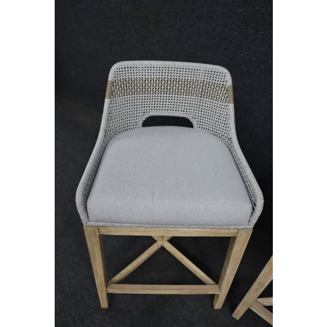 Set of three woven counter stools by Essentials For Living featuring a light natural wood frame, woven open-back seat...