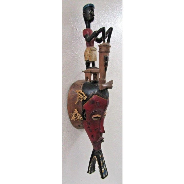 Antique Hand-Carved Guro Mask of the Ivory Coast Featuring a Seated Figure Measures 7 1/4" wide, 6 1/4" deep and 30" tall....