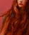In "Curiosity," a figure with flowing, vibrant red hair gazes thoughtfully against a bold pink background, creating a...