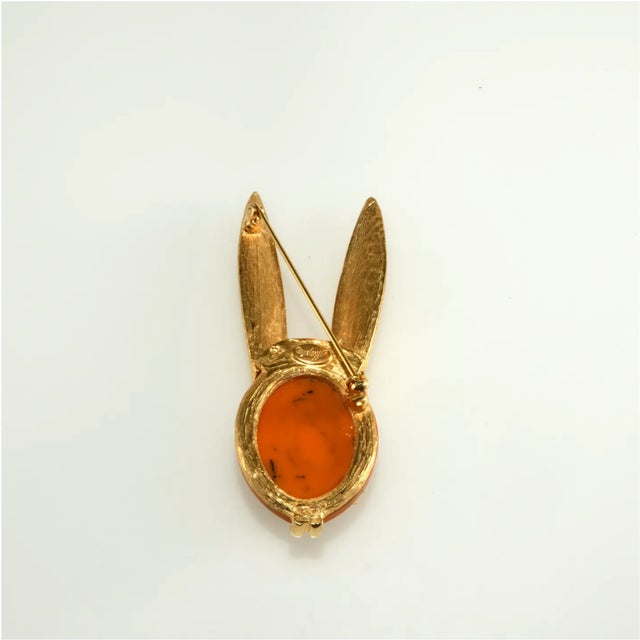 Vintage brooch in the shape of a rabbit with extra large ears. Metal is gold plated with textured finish. The face is...