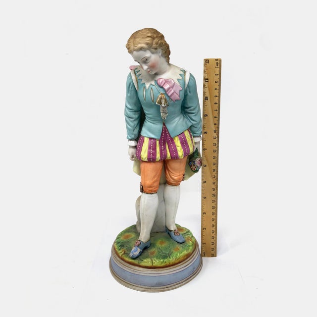 This is a tall, hand-painted antique bisque porcelain figurine standing at 13 inches. It features a gracefully posed young...
