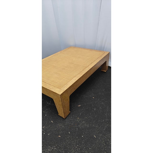 A beautifully proportioned vintage coffee table featuring a woven cane inset top framed by warm-toned wood. The...