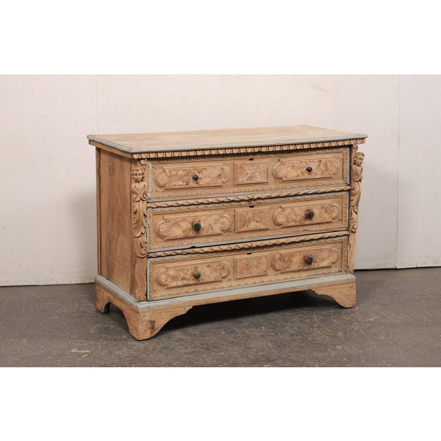 An Italian carved wood chest adorned with putti accents from the 18th century. This antique cassettiera (chest of drawers)...