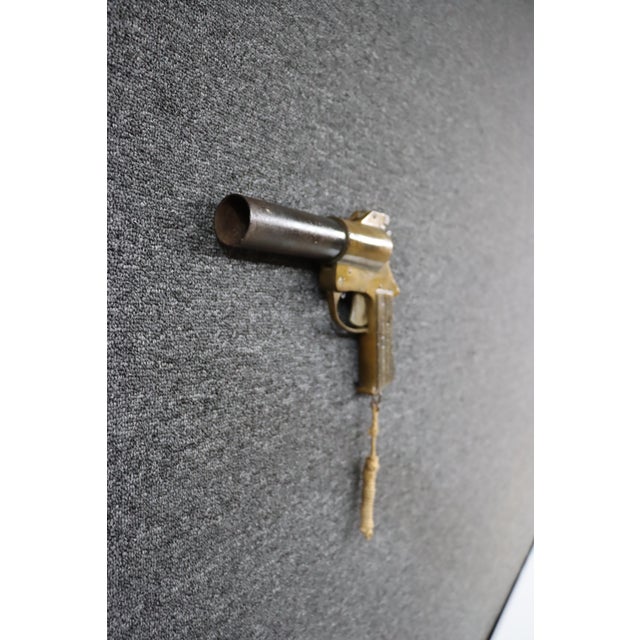 Antique flare gun manufactured by International Flare Signal Co., featuring a brass-finished body, dark iron barrel, and...