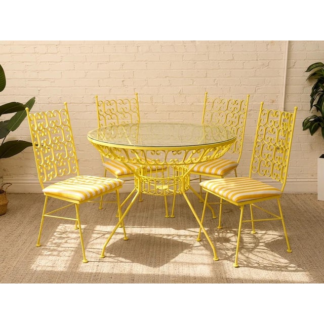 A wonderfully sunny Arthur Umanoff patio set featuring a round glass-top dining table and four matching chairs in cheerful...