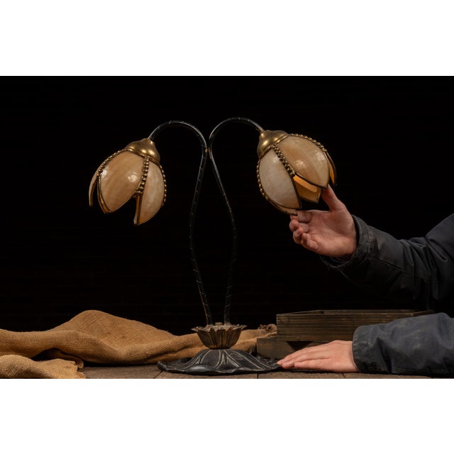 Art Nouveau-inspired table lamp featuring a pair of downward-facing tulip-form shades fitted with warm amber slag glass...
