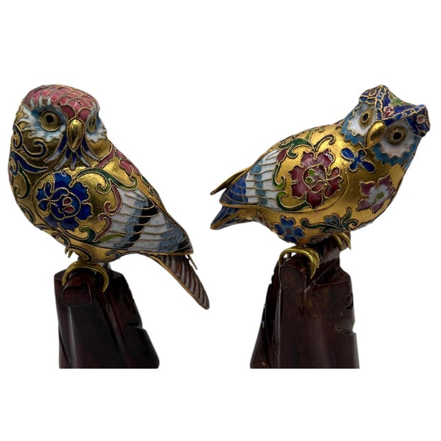 A pair of traditional Chinese cloisonné owl figurines featuring intricate enamel work and gold leaf details perched on...