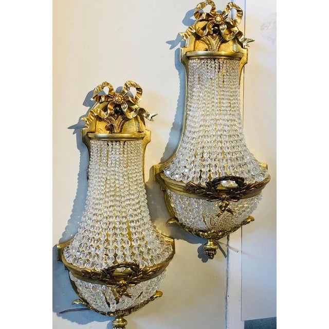 Pair of Louis XVI style bronze and crystal beaded diminutive wall sconce. This finely case pair of beaded wall sconce are...