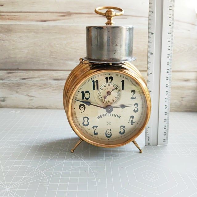 This rare antique German mechanical alarm clock—manufactured around 1900 by the renowned Hamburg-Amerikanische Uhrenfabrik...