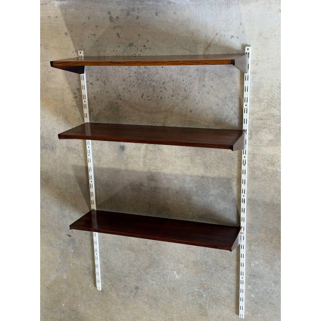 Vintage 1960s Mid-Century Modern wall shelving system in style of Kai Kristiansen, featuring richly grained rosewood...