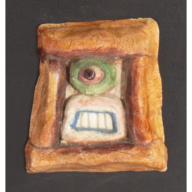 A 1970s ceramic tile by the American artist Mark Bulwinkle (born 1946). This ceramic piece depicts an abstract face...