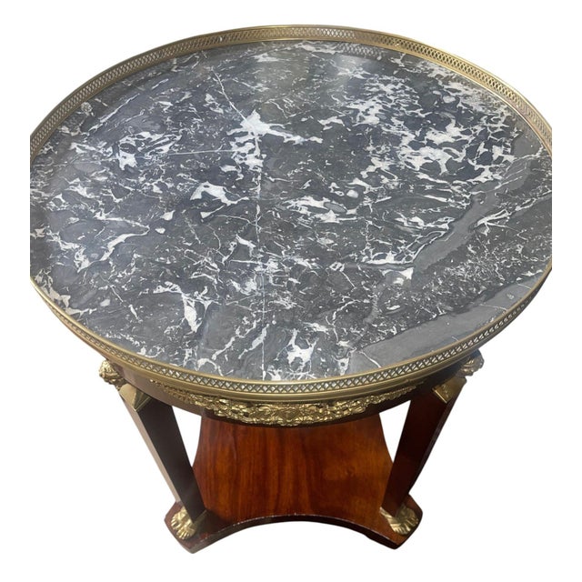 Elegant late 19th century Empire style side table with a circular gray-and-white marble top, pierced bronze gallery, and...