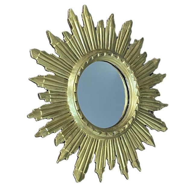 An elegant sun-shaped mirror made of carved and gilded wood, crafted around the 1960s. Retaining its original gilding, it...