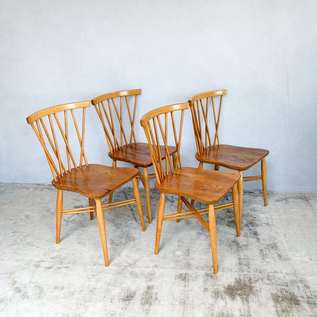 A set of four Candlestick Chiltern dining chairs by Ercol. Eight beech spindles rise from each seat in four crossing pairs...