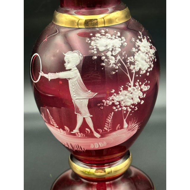 A beautifully preserved late‑19th‑century ruby flashed glass vase featuring a classic Mary Gregory–style white enamel...