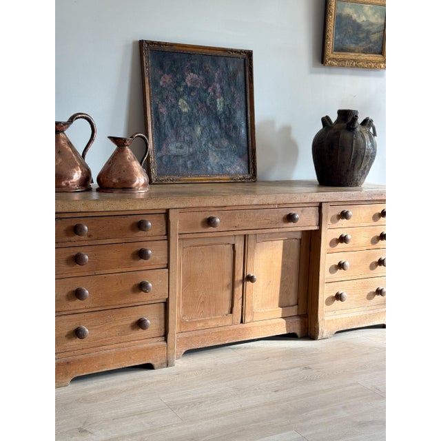 A long pine bench-counter built like furniture — two banks of four drawers flanking a center section with a single shallow...