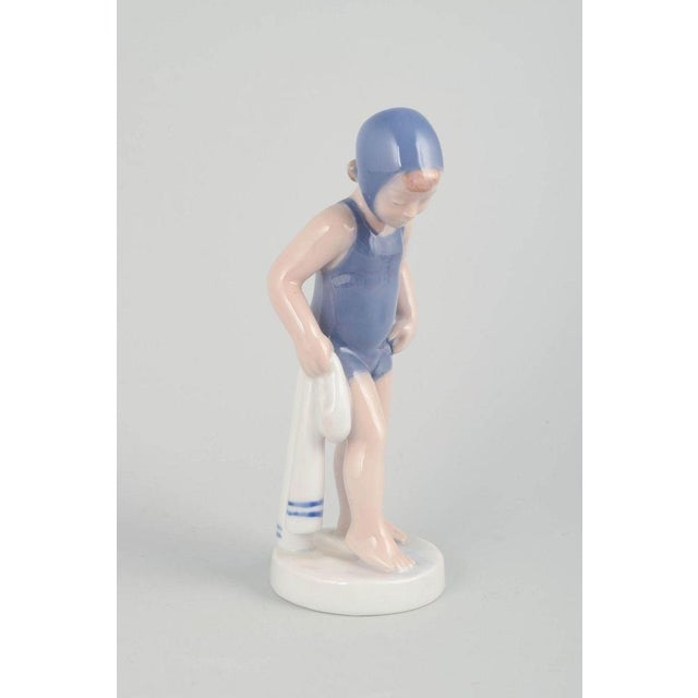 Royal Copenhagen Figur “The Swimmer”, model 4529, 1980s. Porcelain figurine of a young girl in a blue swimsuit and bathing...