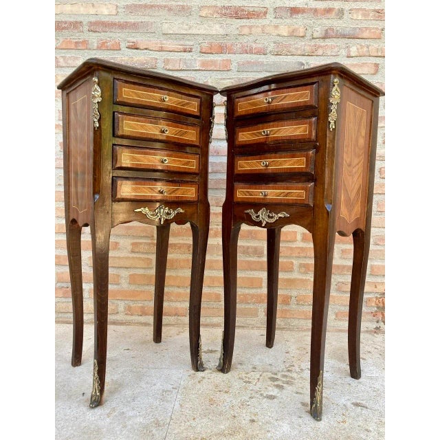 A pair of French Louis XV style nightstands with a marquetry top in TulipWood. The slim body of walnut and tulipwood, each...