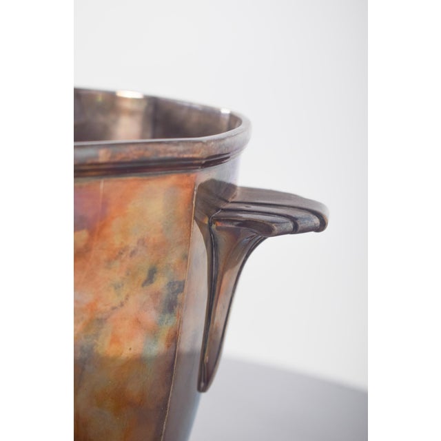 Shell ice bucket. with a slightly conical body, widening at the top and resting on a rounded, firm base. It has two...