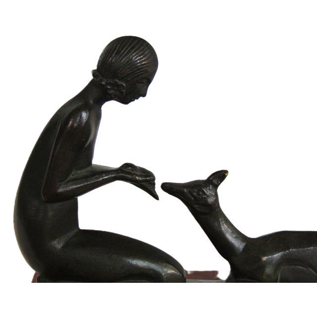 A wonderful antique art deco bronze sculpture of a woman feeding a deer. Sculpture is mounted on a red marble base....