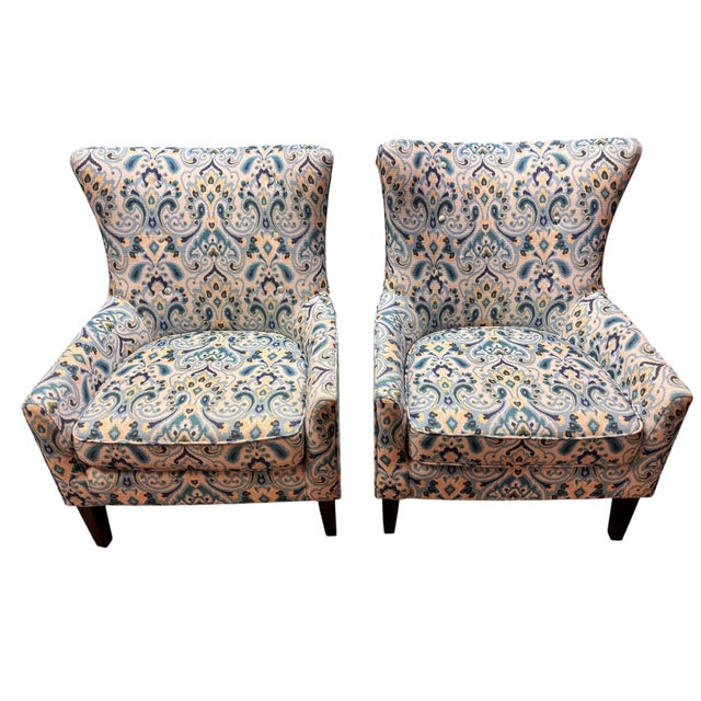 Stylish pair of generously scaled upholstered armchairs featuring a softly flared wingback silhouette, gently curved arms...