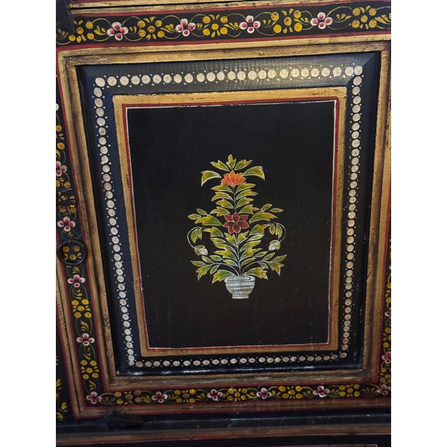 Vintage mid-20th-century Asian-style black lacquer cabinet, hand-painted with delicate gilt floral motifs and trim. The...