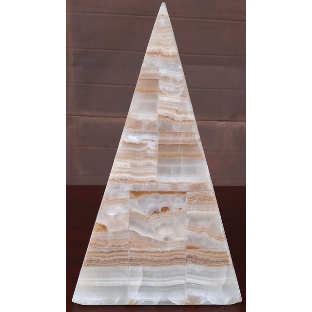 A handcrafted onyx pyramid form lamp, typically crafted from a single piece of natural stone featuring unique parallel...
