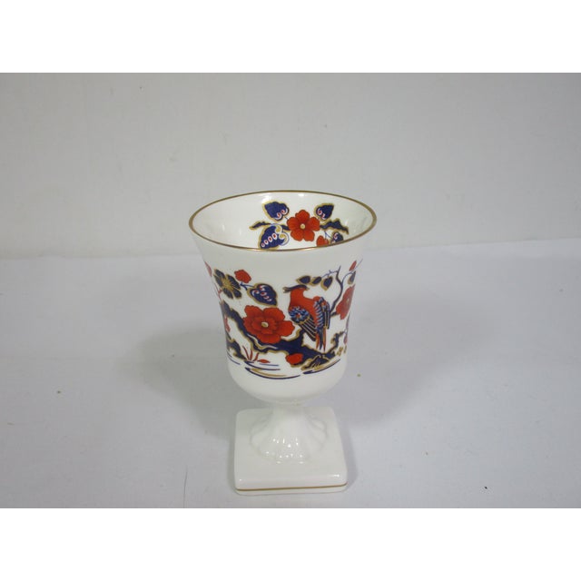 An elegant Aynsley bone china stemmed vase made in England. It is decorated with an intricate design of a bird paradise...