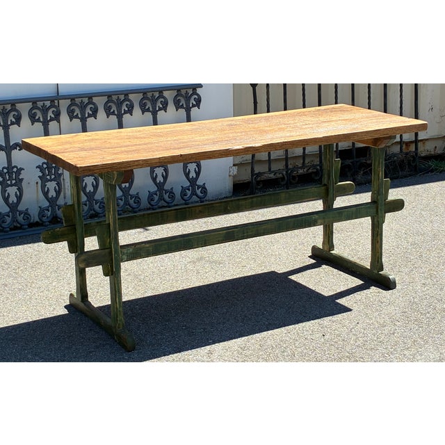 The base of this well-used work table consists of two trestle-style ends, each with a sturdy cross member on top and a...