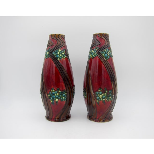 An antique English Secessionist Ware vase pair from Minton's of Stoke-on-Trent, Staﬀordshire. These striking art pottery...