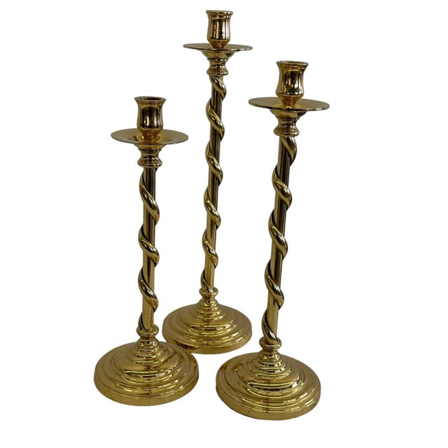 Trio of three brass twisted candlestick holders. This set is made from solid polished brass. The trio features a twisted...