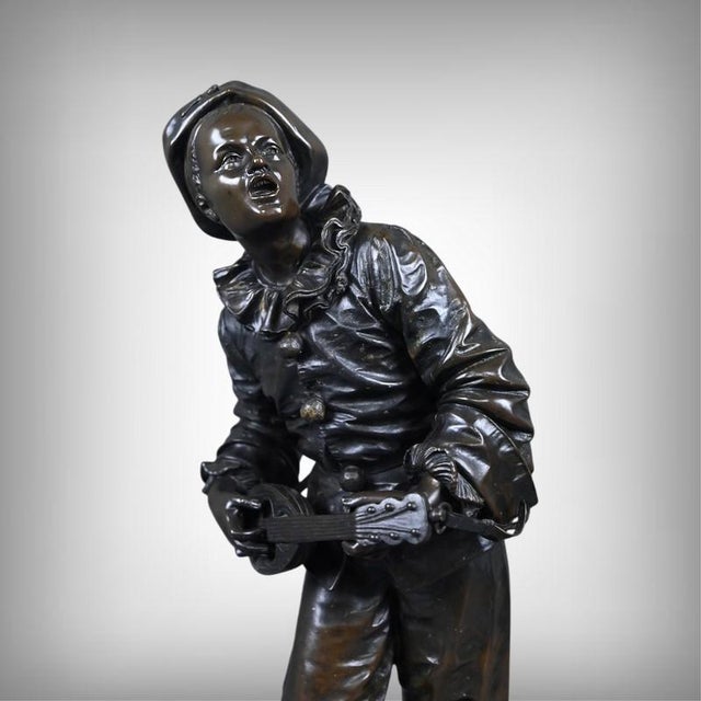 This charming bronze with a brown patina depicts Pierrot as a musician, captured in a moment of carefree joy. The figure,...