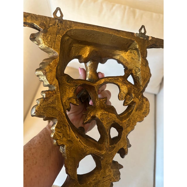 A striking pair of vintage giltwood wall brackets featuring ornate Rococo-inspired carving with scrolling acanthus leaves,...