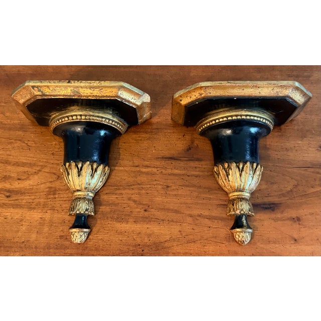 Sweet pair of ebony and gilt ceramic wall shelves. Classic acanthus leaf design with a beaded trim, these have a wonderful...