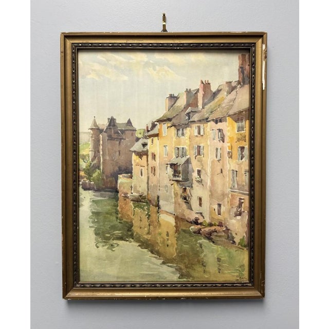This charming circa 1931 French watercolor, titled La Espalion and signed lower right “Marc,” depicts sun-washed riverside...