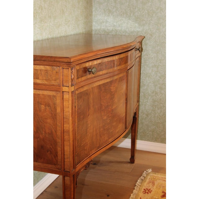 A serpentine-front sideboard in the Hepplewhite manner, circa 1919, at a compact and genuinely usable scale. A single long...