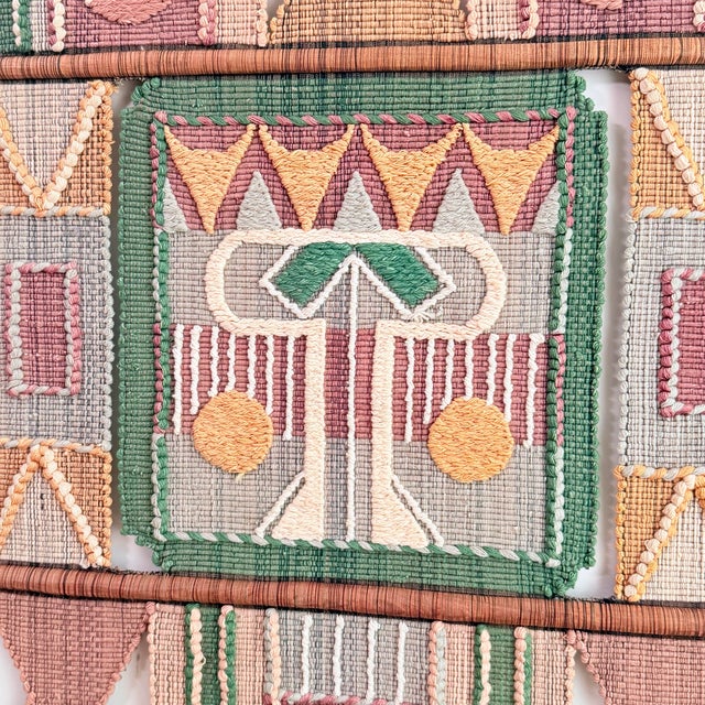 A striking vintage fiber art wall hanging featuring bold geometric motifs in a soft, earthy palette of sage green, dusty...