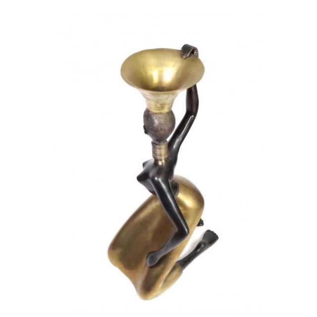 Striking vintage sculptural figure depicting a graceful kneeling woman carrying a large vessel or basket atop her head....