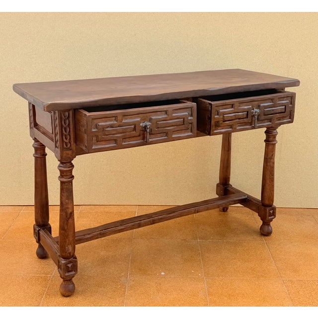 Elegant Spanish console table crafted in walnut and featuring two richly carved drawers with striking geometric motifs and...