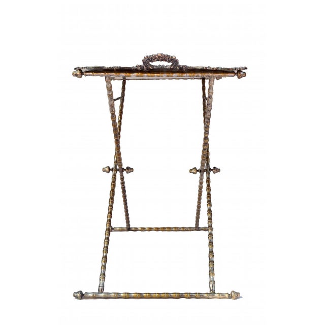 This silvered bronze table is composed of a large rectangular tray, placed on a bamboo style X-shaped stand. The...