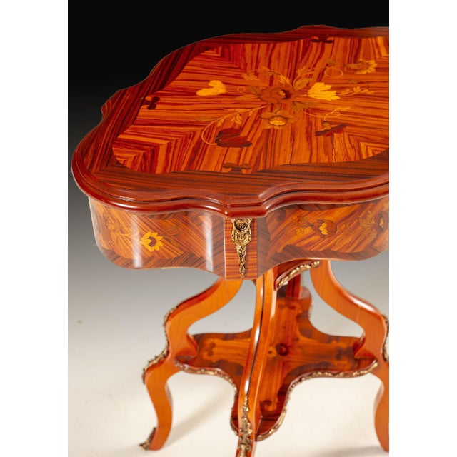 Handcrafted in Italy, this accent chairside table features floral inlays across the shaped top, apron, and lower shelf....