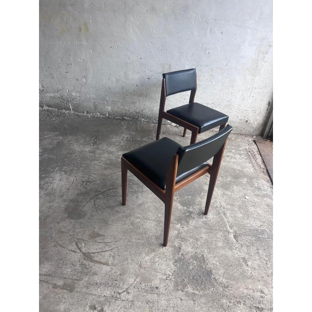 A refined pair of mid-century dining chairs featuring elegant solid wooden frames with traditional mortise-and-tenon...