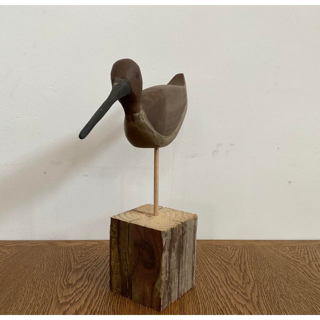 Bring a touch of coastal serenity and rustic texture into your space with this captivating hand-carved shorebird...
